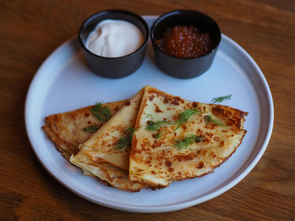 Close-up of traditional blinis served with sour cream and red caviar.