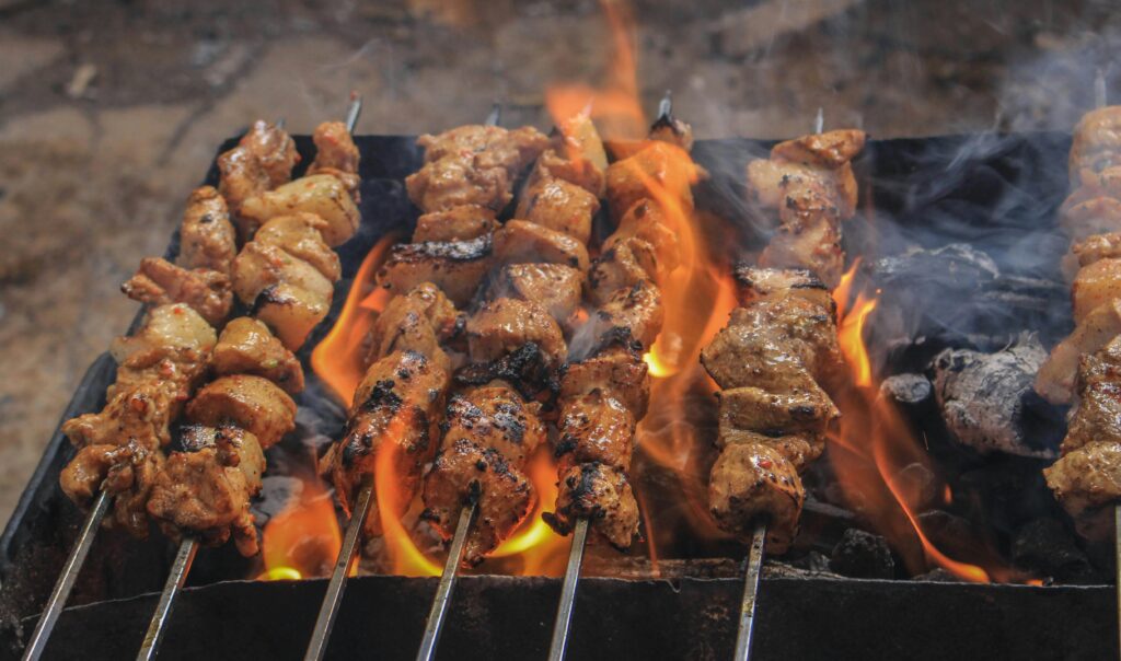 Juicy skewers of grilled meat sizzling over open flames, creating a tasty barbecue feel.